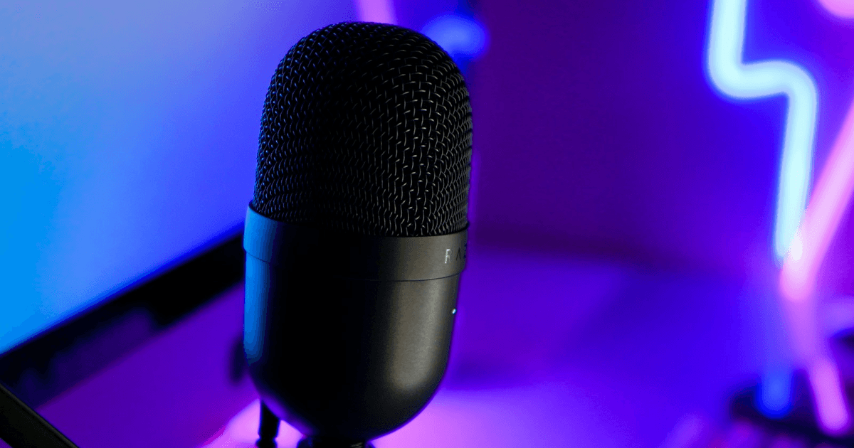 Black streaming microphone lit by purple and blue gaming-room lights